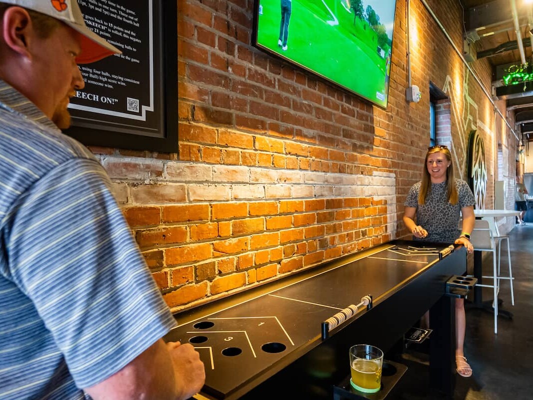 Two people casually playing shuffleboard