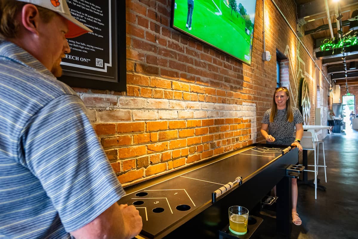Two people casually playing shuffleboard